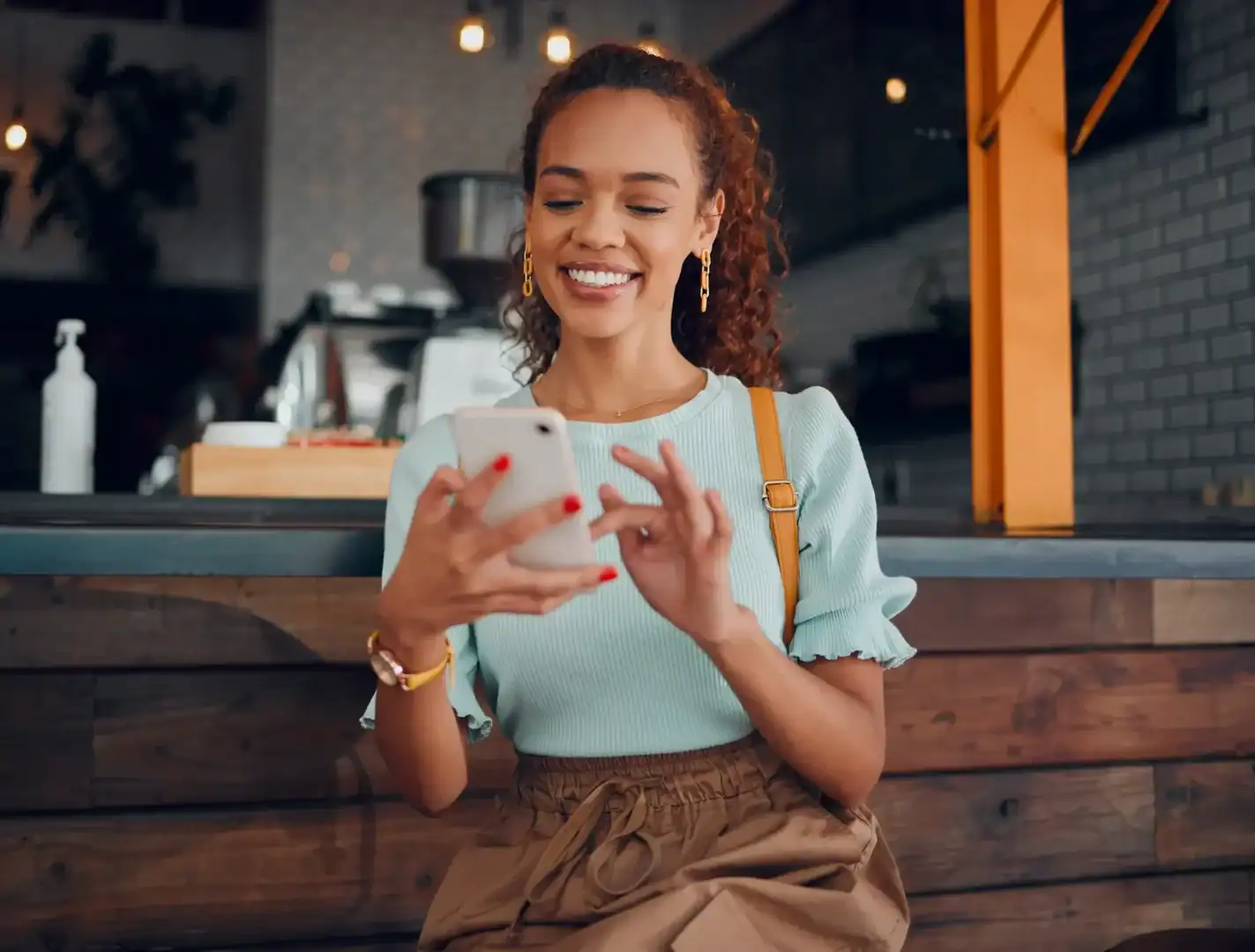 Woman smiling while using a smartphone in a cafe