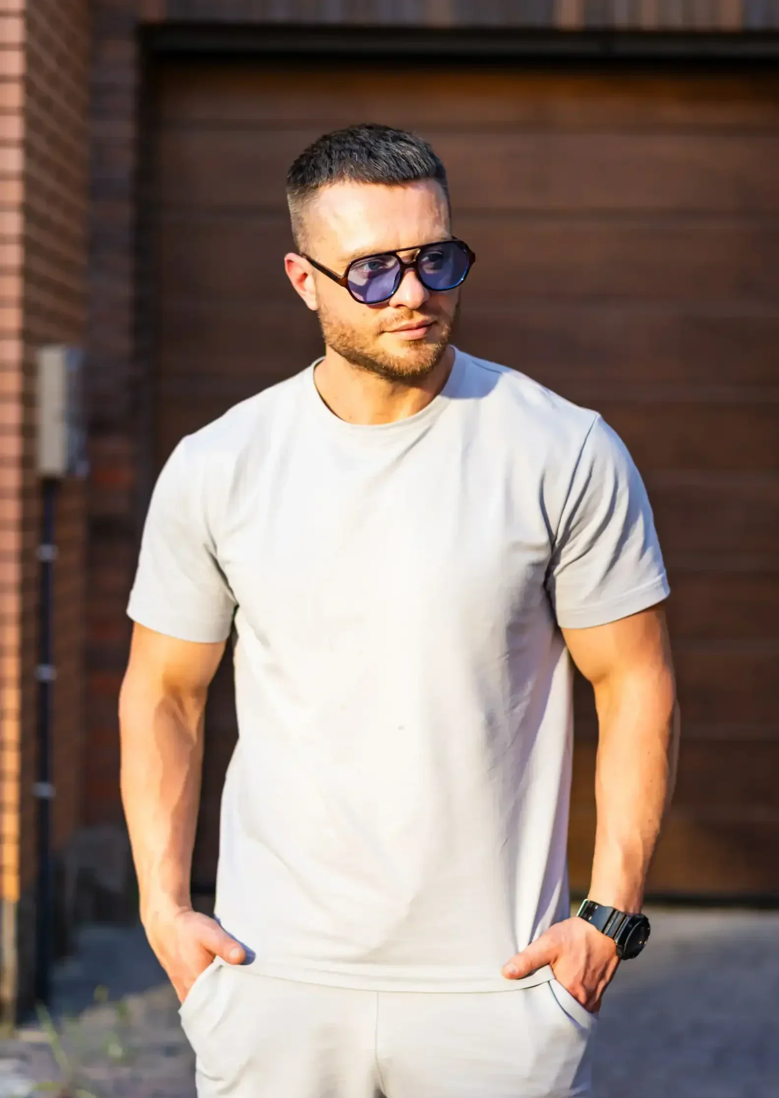 Man wearing sunglasses and a light t-shirt standing outdoors