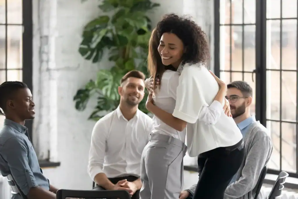 Two group therapy participants embracing while other members look on during a depression treatment session