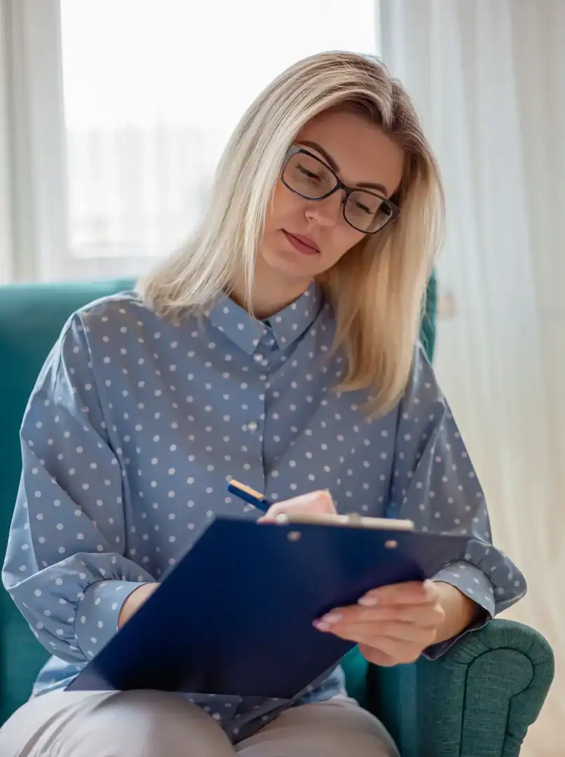 Clinician takes notes during a mental health diagnostic assessment for a client.