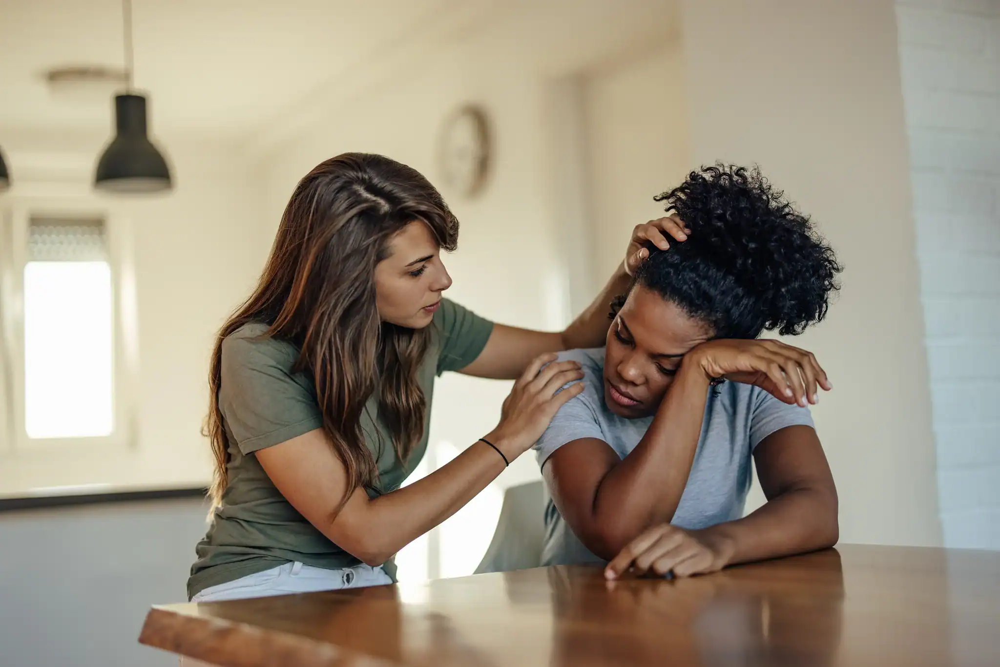 A woman comforting a friend who is struggling with depression at home.