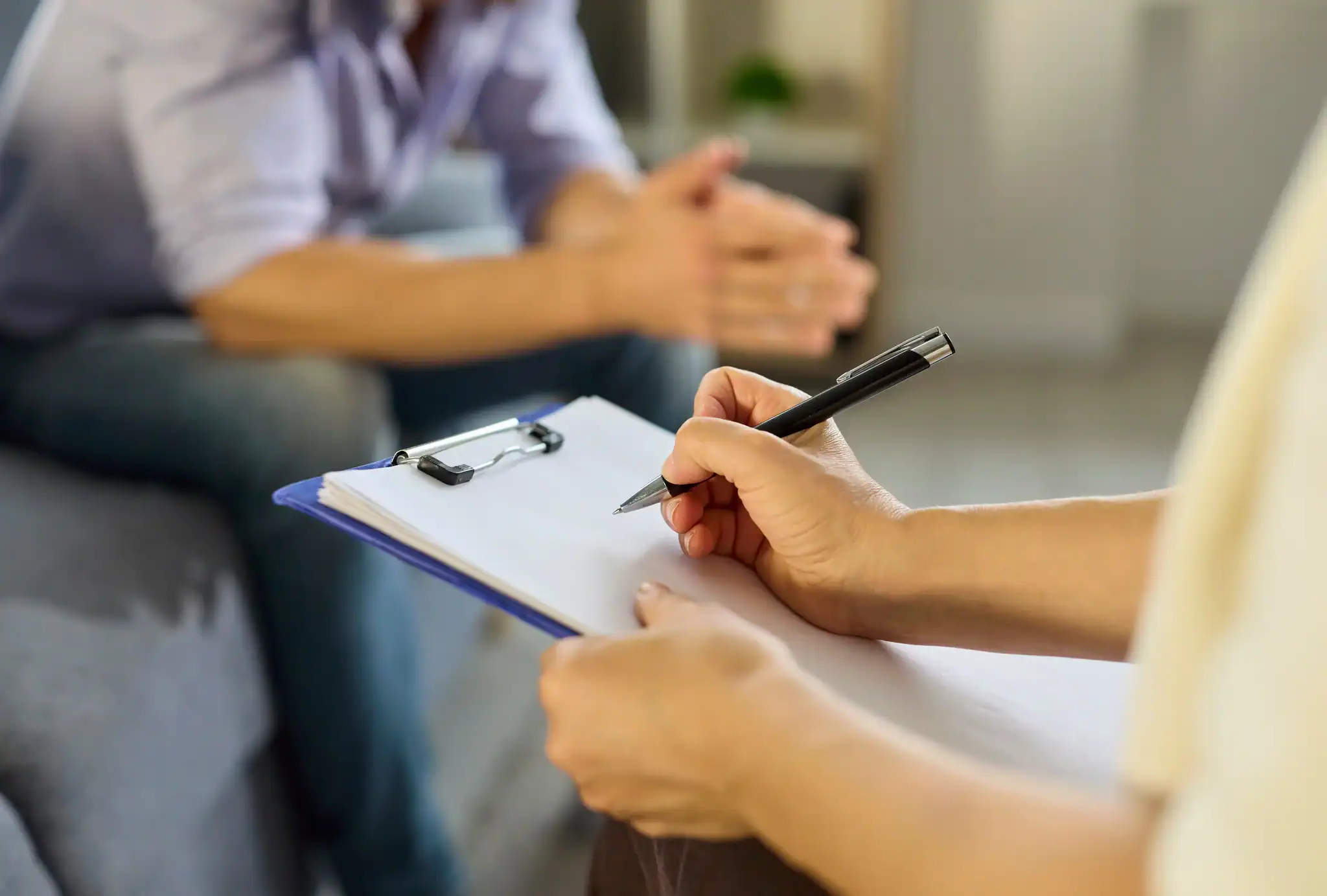 Adult completing a depression self-assessment questionnaire on a clipboard during a mental health screening.