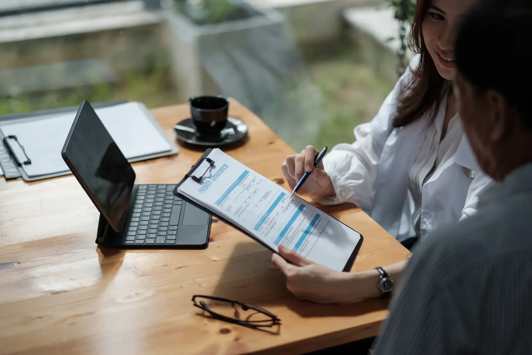 A health insurance benefits form being reviewed on a clipboard during an insurance verification conversation.