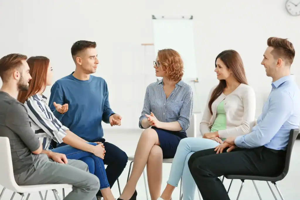 Adults participate in a structured outpatient group therapy session led by a clinician.