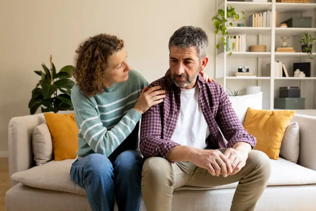 Partner comforting a spouse with depression while sitting together on a couch at home.