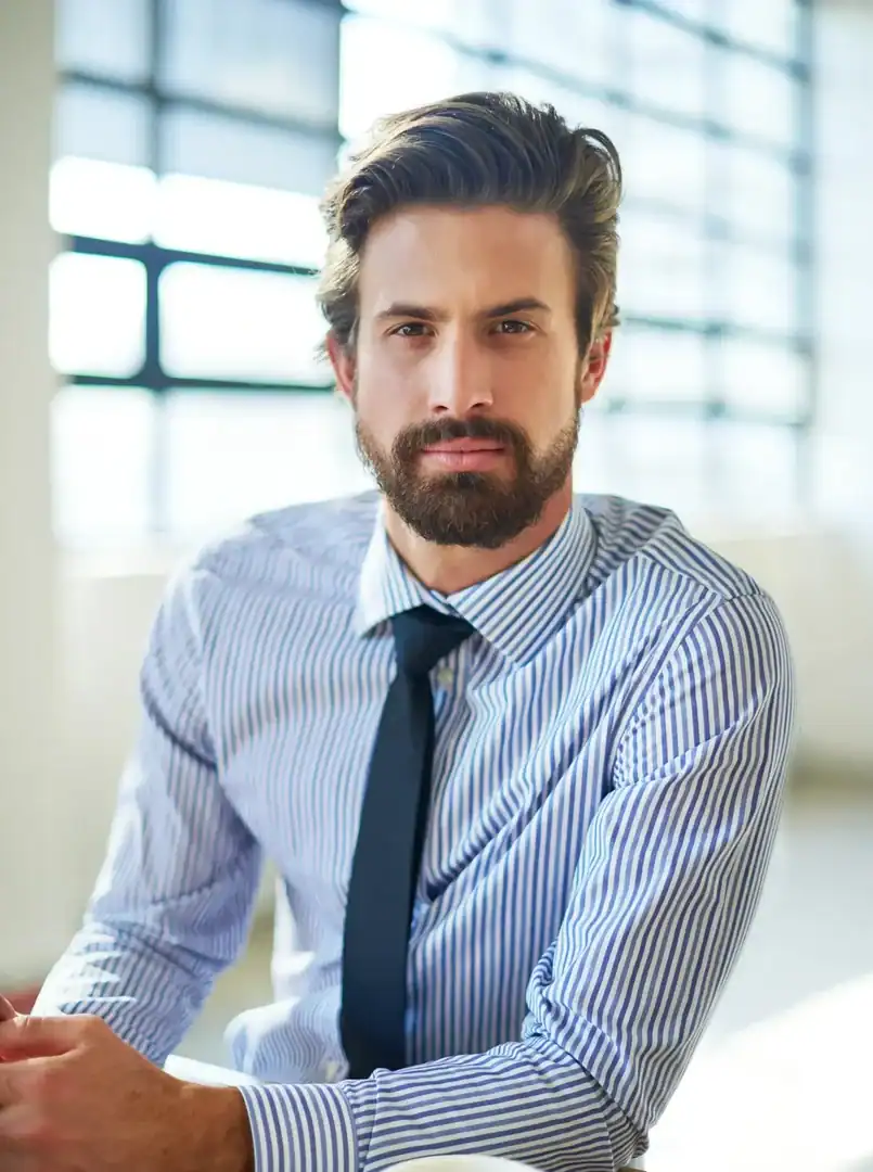 Man in a striped shirt seated at a table, considering adult mental health treatment options.