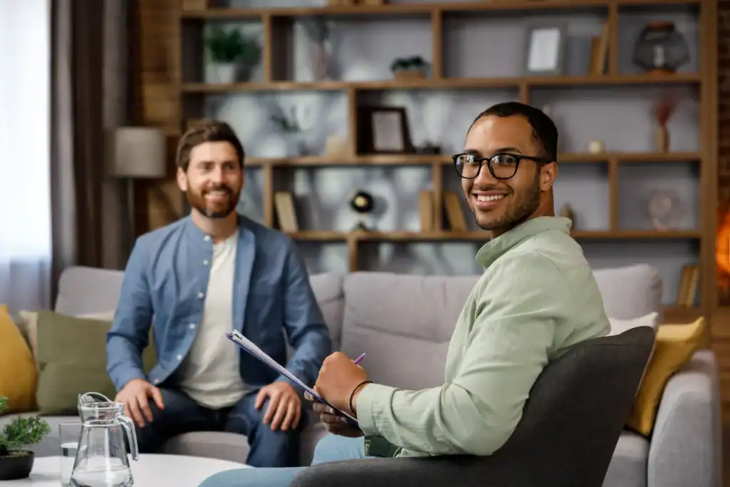 Therapist taking notes during a mental health therapy session with a male client.