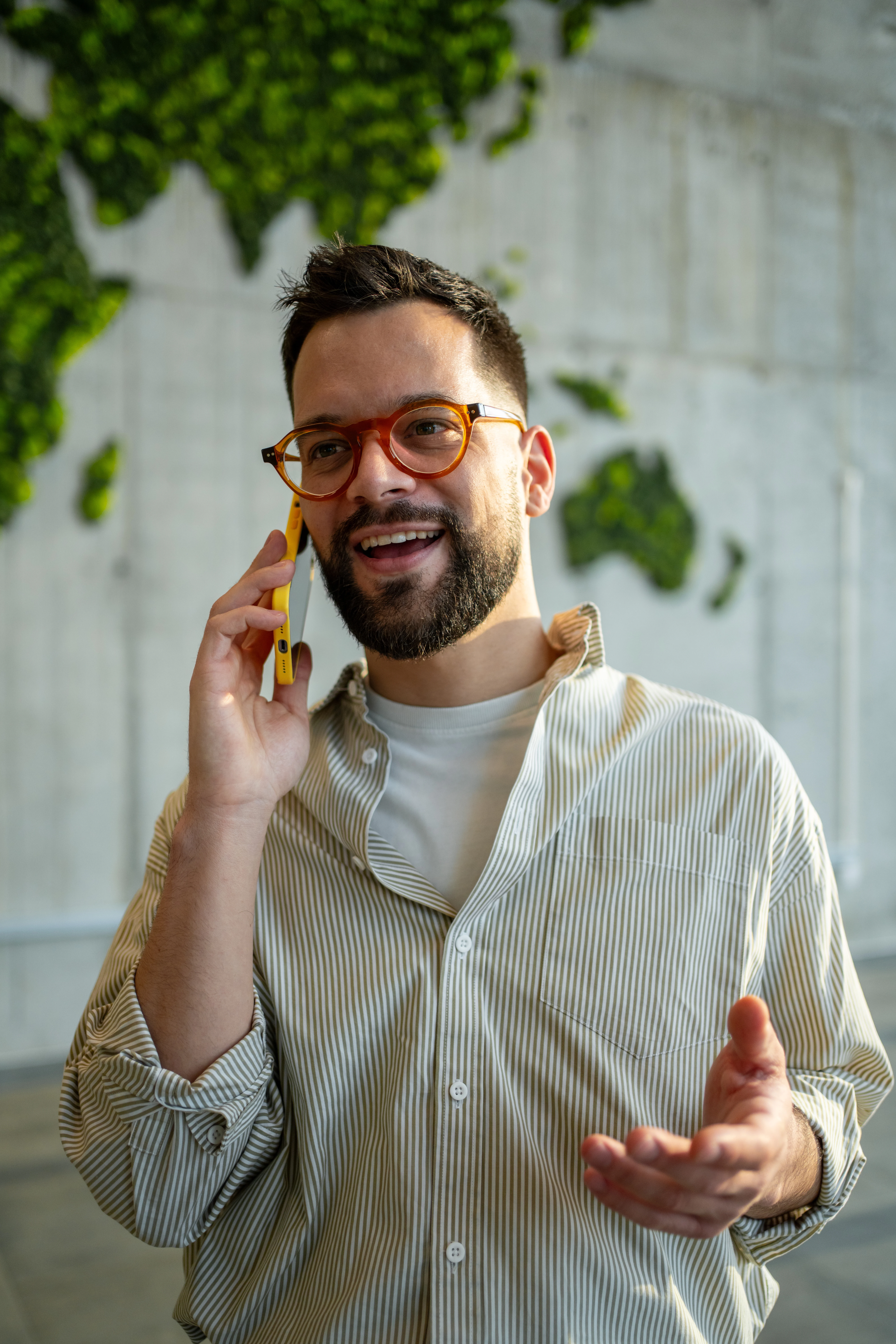 Man smiling while talking on a mobile phone indoors.