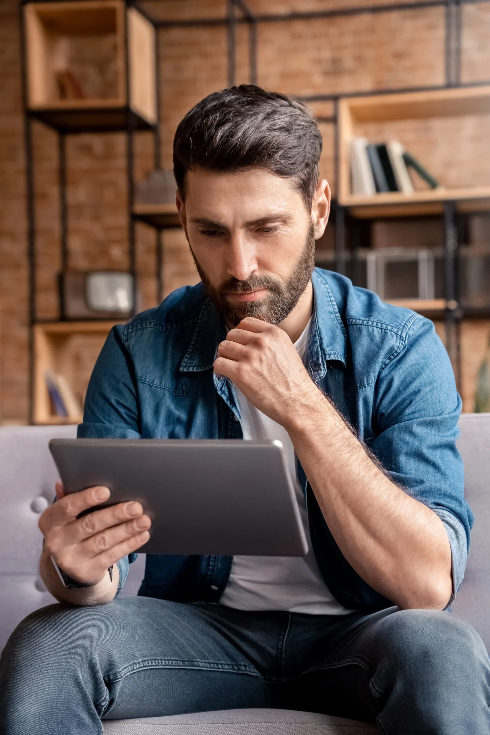 Man reviewing insurance and treatment information on a tablet at home.