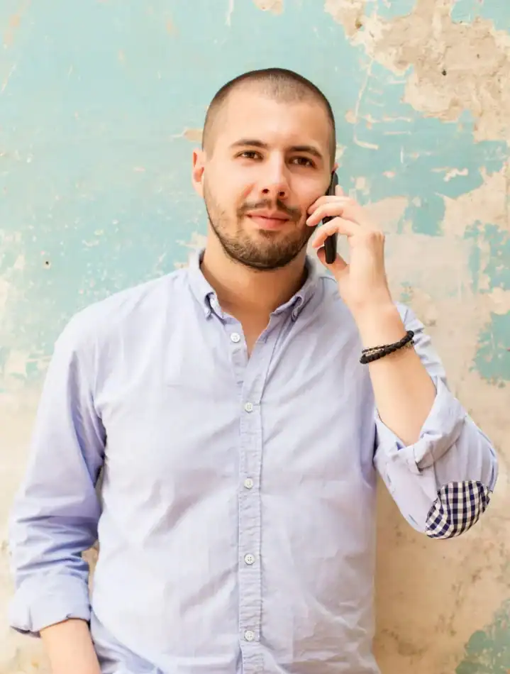 Man in a button-down shirt talking on his cell phone..